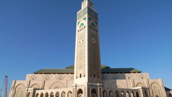 A photo of the exterior of the Hassan II Mosque in Casablanca, Morocco. The mosque is an impressive example of Islamic architecture, with a symmetrical facade, intricate details, and a towering minaret.