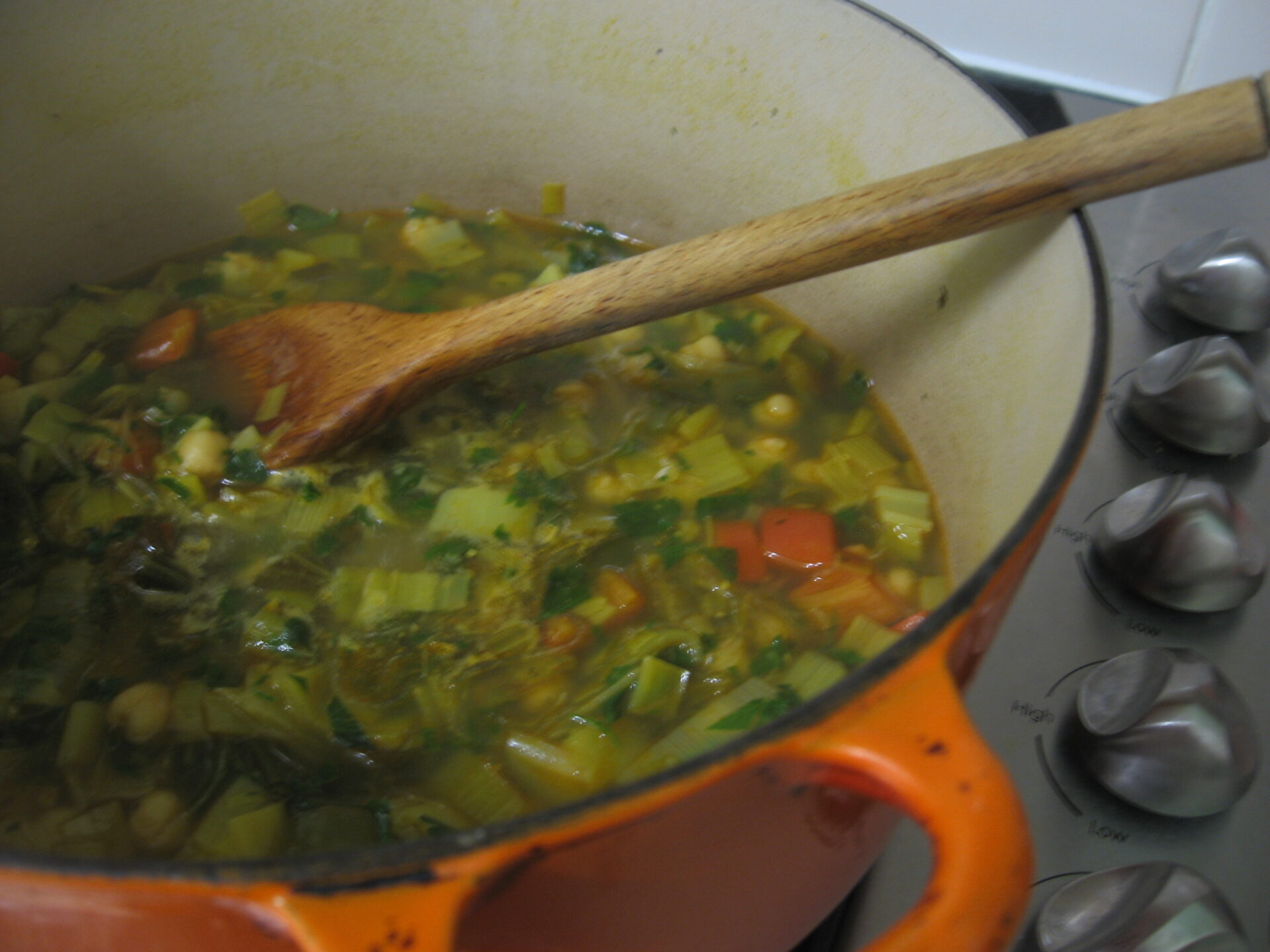 Image of a pot of Moroccan Harira Soup cooking on a stove, with ingredients and utensils nearby. This image represents the process of cooking the perfect Harira Soup at home, highlighting the preparation and cooking techniques used.