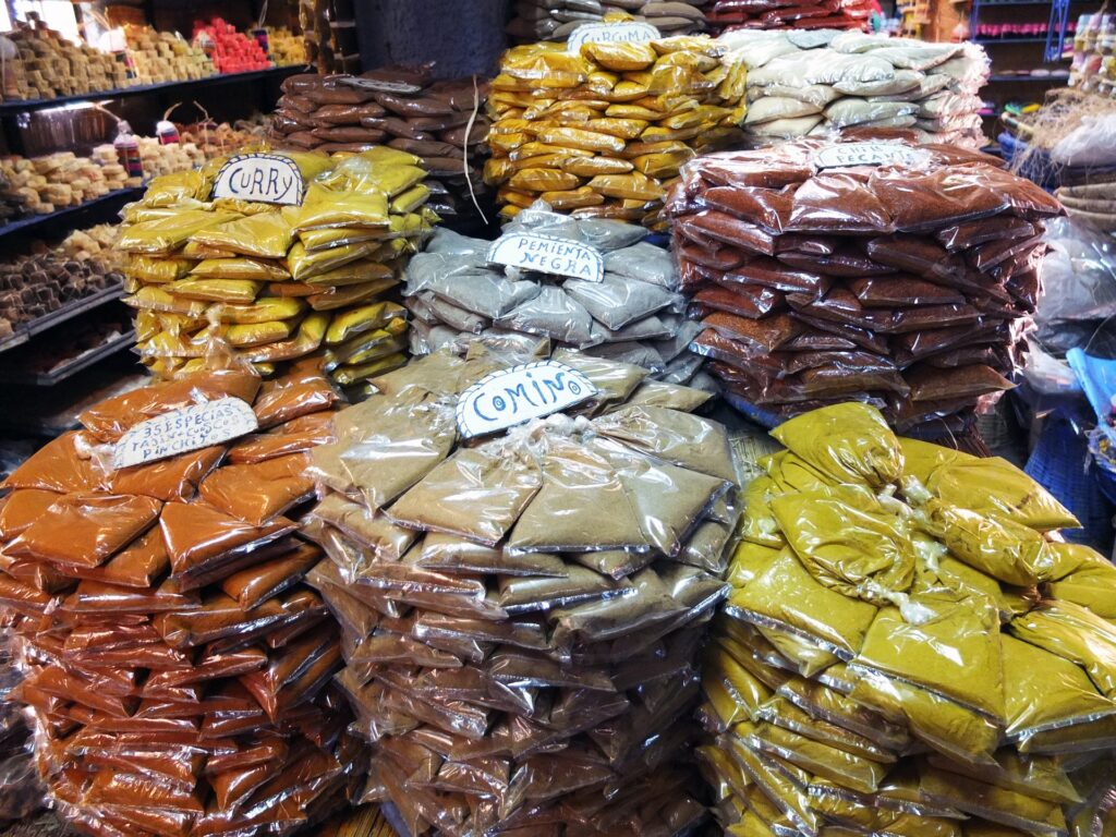 Stacks of Moroccan spices, including cumin, turmeric, paprika, and cinnamon, stocked in plastic bags on a market shelf.