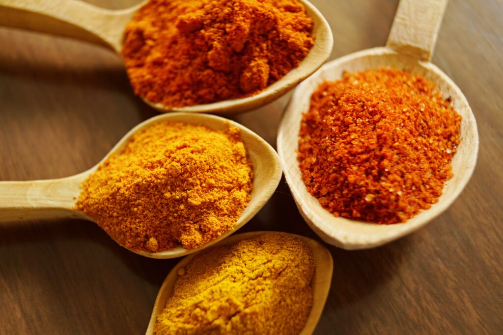 A photo of several spoons filled with various colorful spices commonly used in Moroccan cuisine, emphasizing the importance of spices in Moroccan cooking.