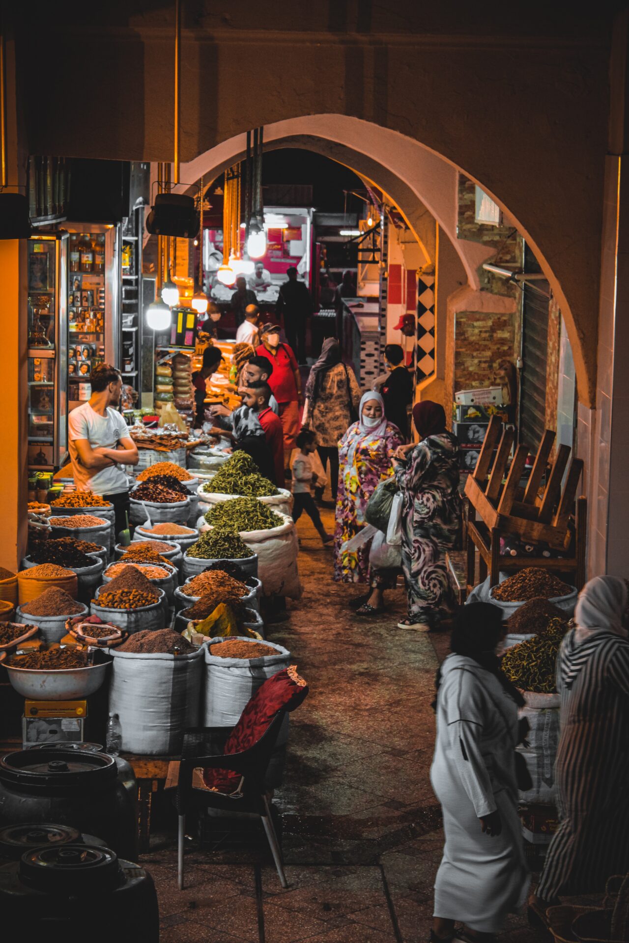 People browsing through colorful textiles and spices at Meknes' bustling souks.