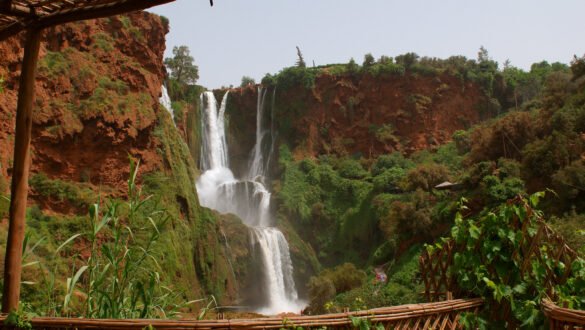 A stunning aerial view of Ouzoud Falls, one of the hidden waterfalls in Morocco, surrounded by lush green vegetation and rocky cliffs, with water cascading down from the top to the bottom.