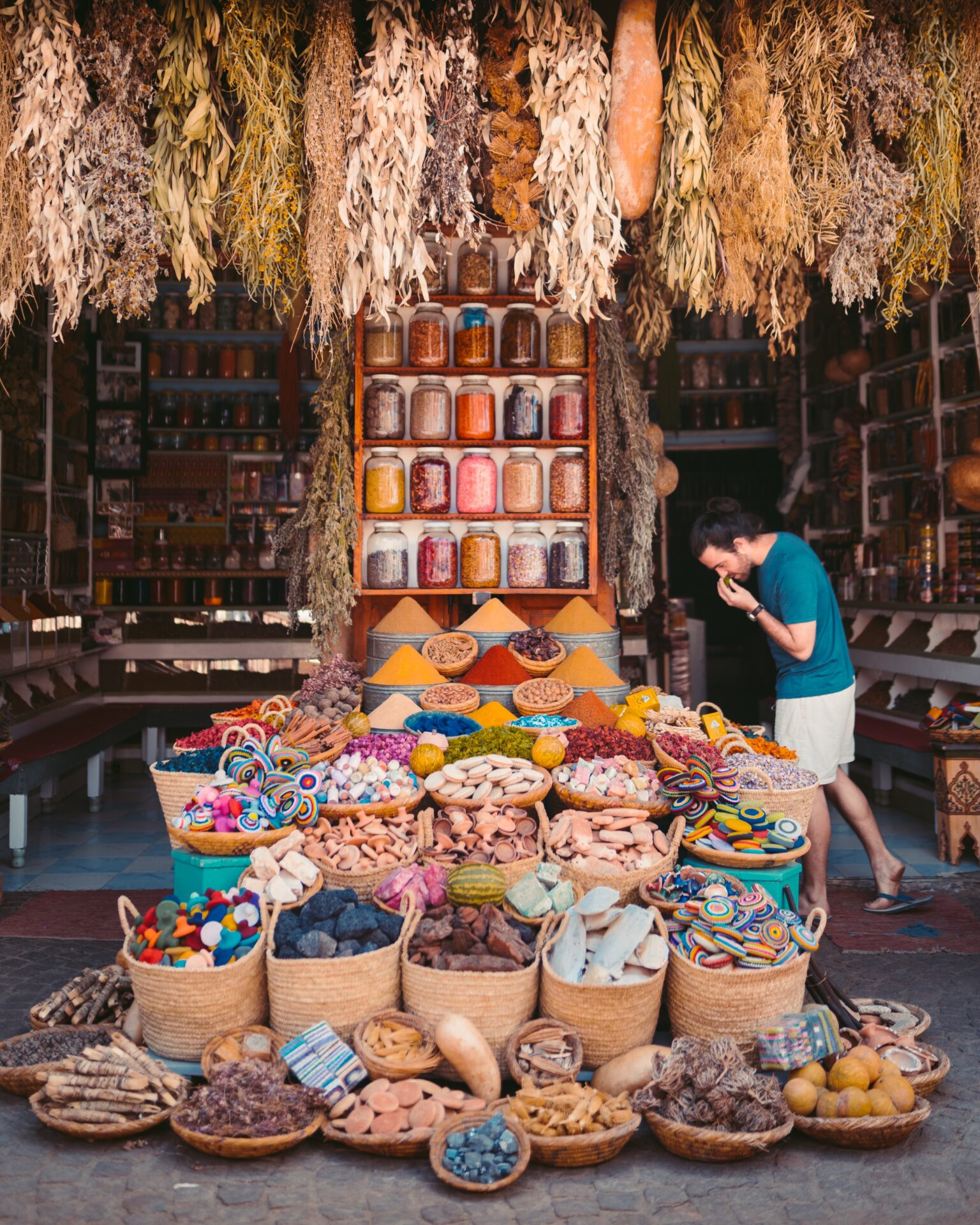 A store display of various Moroccan spices including paprika, cumin, coriander, saffron, turmeric, and cinnamon.