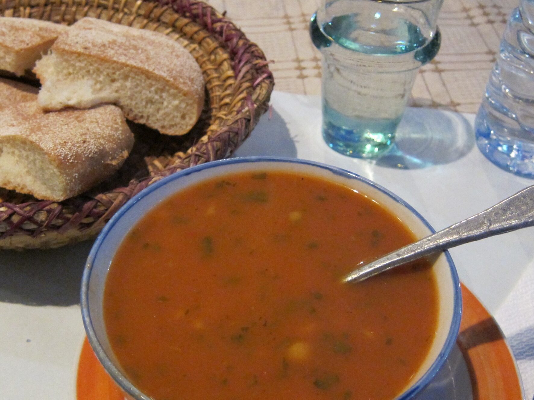 Image of a plate with Moroccan side dishes and bread, including olives, dates, and flatbread, served alongside a bowl of Harira Soup. This image represents the traditional way of pairing Harira Soup with Moroccan side dishes and breads, highlighting the cultural significance of the dish.