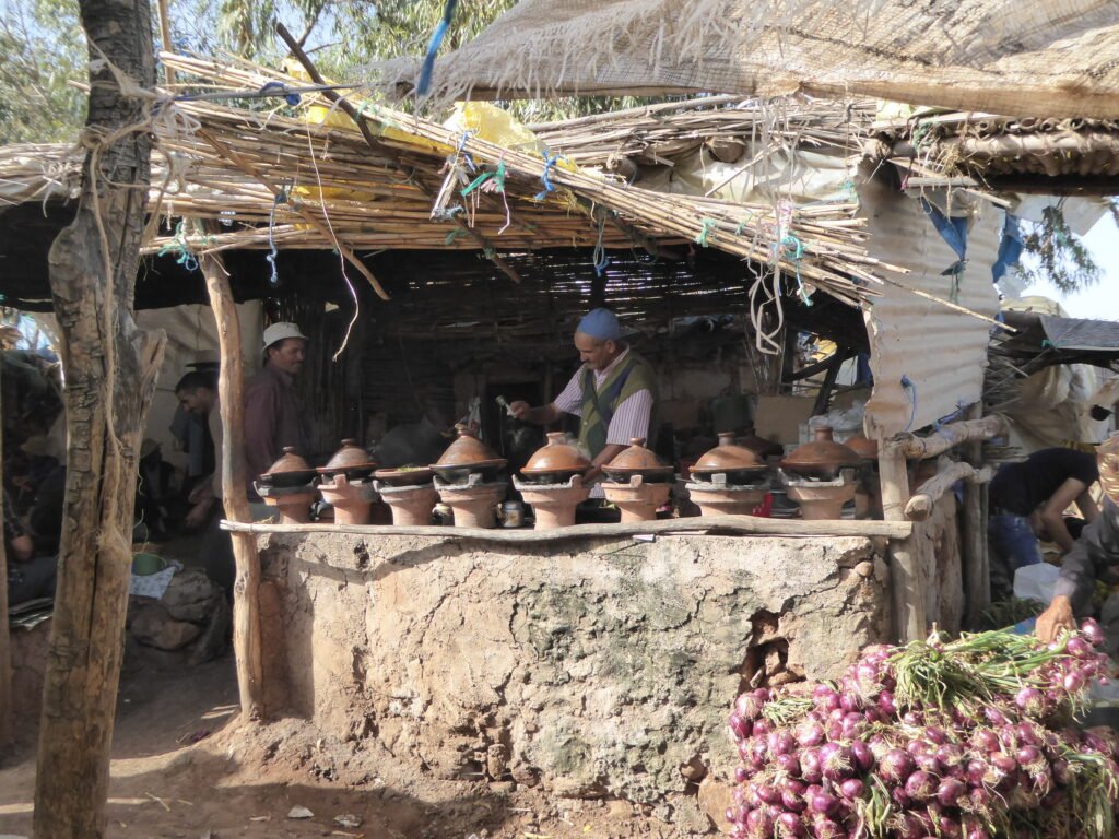 A man preparing tagines for the day's meals in a small town marketplace.