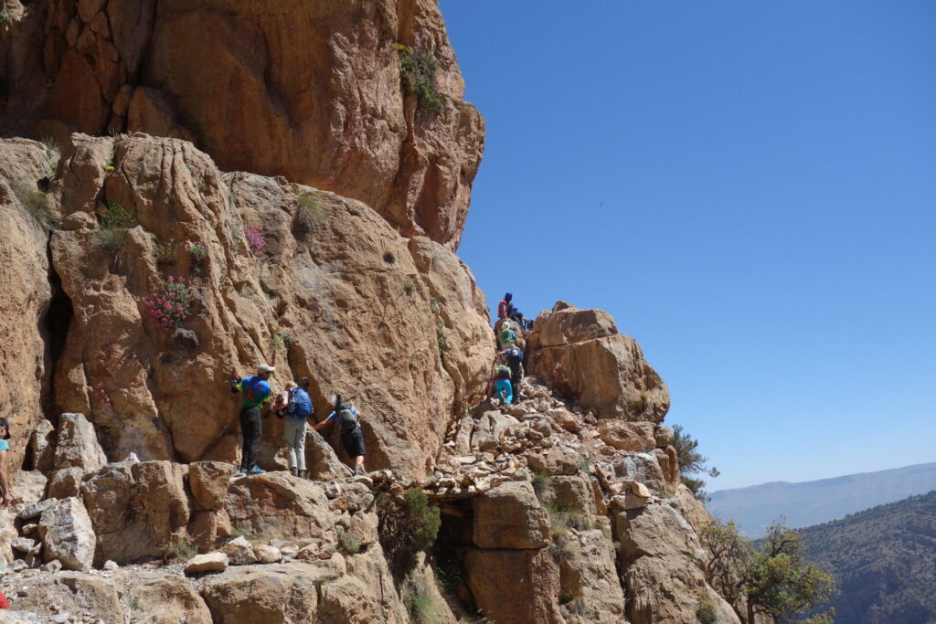 A group of adventurers traversing the Passage Berbère in Taghia, surrounded by breathtaking cliffs and stunning natural beauty.