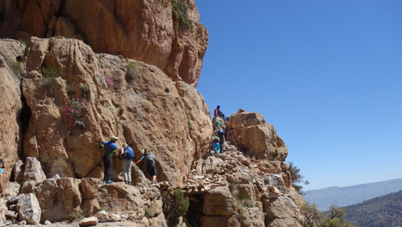 A group of adventurers traversing the Passage Berbère in Taghia, surrounded by breathtaking cliffs and stunning natural beauty.