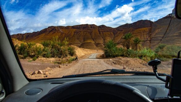 A scenic drive through the Anti Atlas mountain range in Morocco, with a road winding through rugged terrain and sparse vegetation. The road leads towards Marrakech, offering stunning views of the mountains and valleys below. The image captures the sense of adventure and natural beauty experienced while traversing this remote and picturesque landscape.