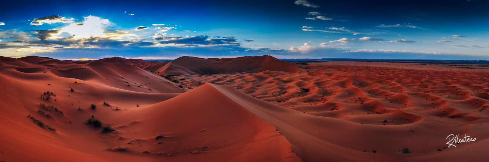 A panoramic view of the Sahara Desert at sunset, showcasing its vast expanse and captivating beauty